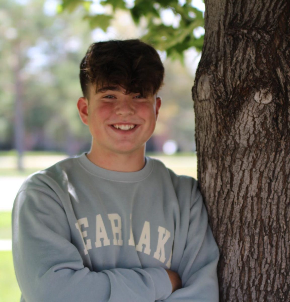 Image of Oliver Lodato (10) standing by a tree and smiling.