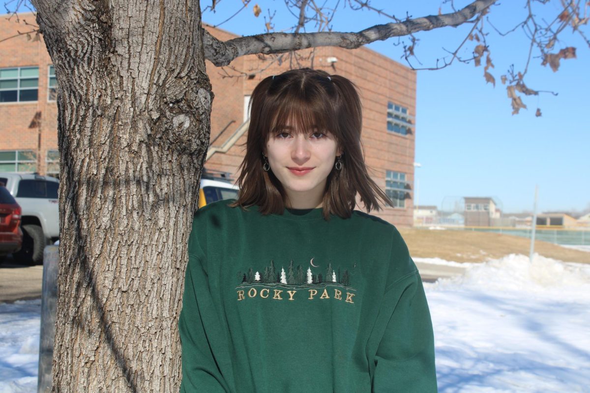 Sophia Jensen (12) stands against a tree and smiles