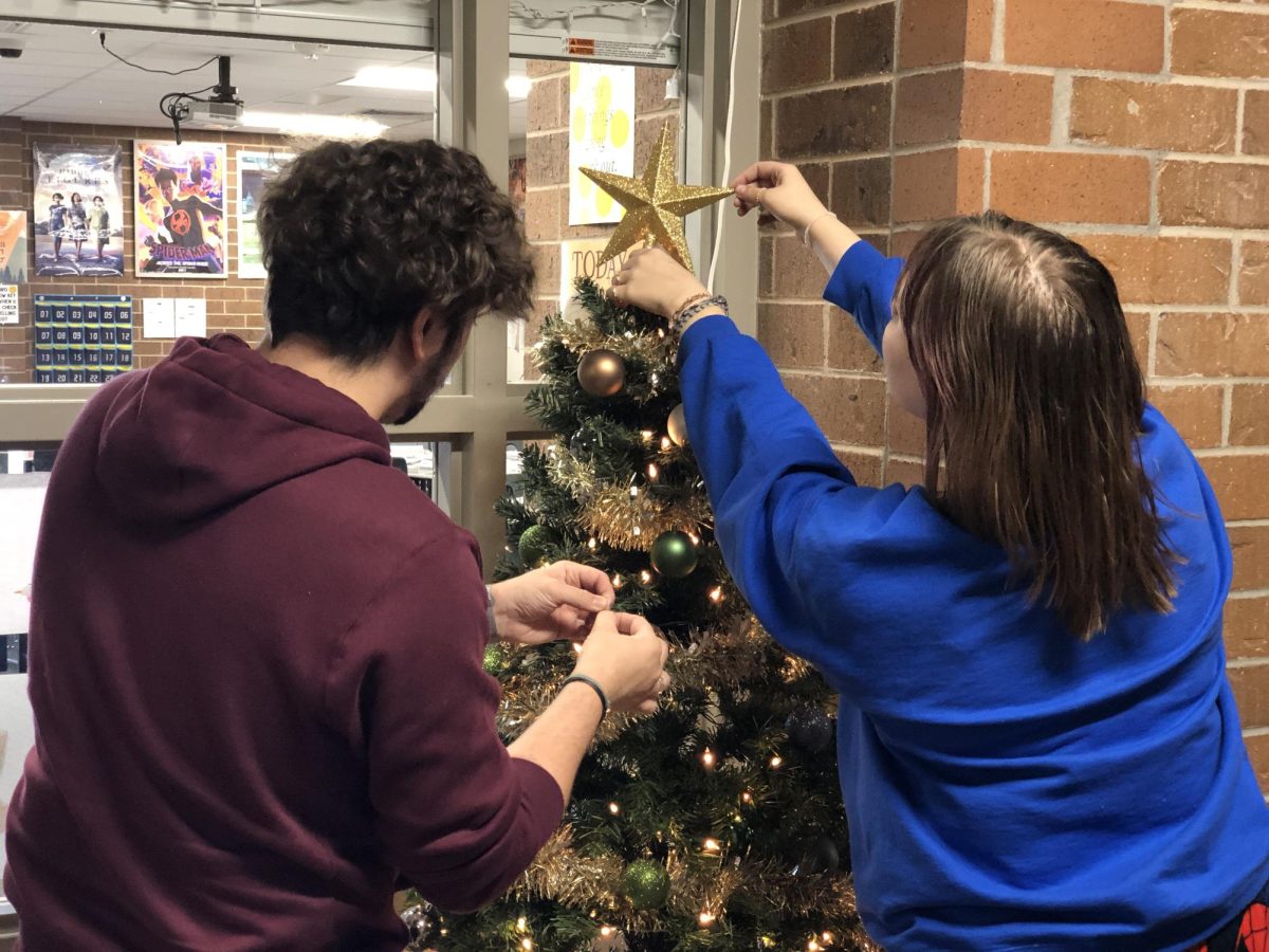 Shyre Hodson (11) and Ethan Mattix (staff) decorate their advisory Christmas tree. The advisory always decorates their Christmas tree as a class tradition, and Mattix plans on continuing the tradition after his advisory class graduates next school year.