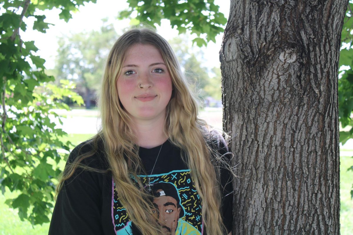 Alyssa Smith stands against a tree and smiles