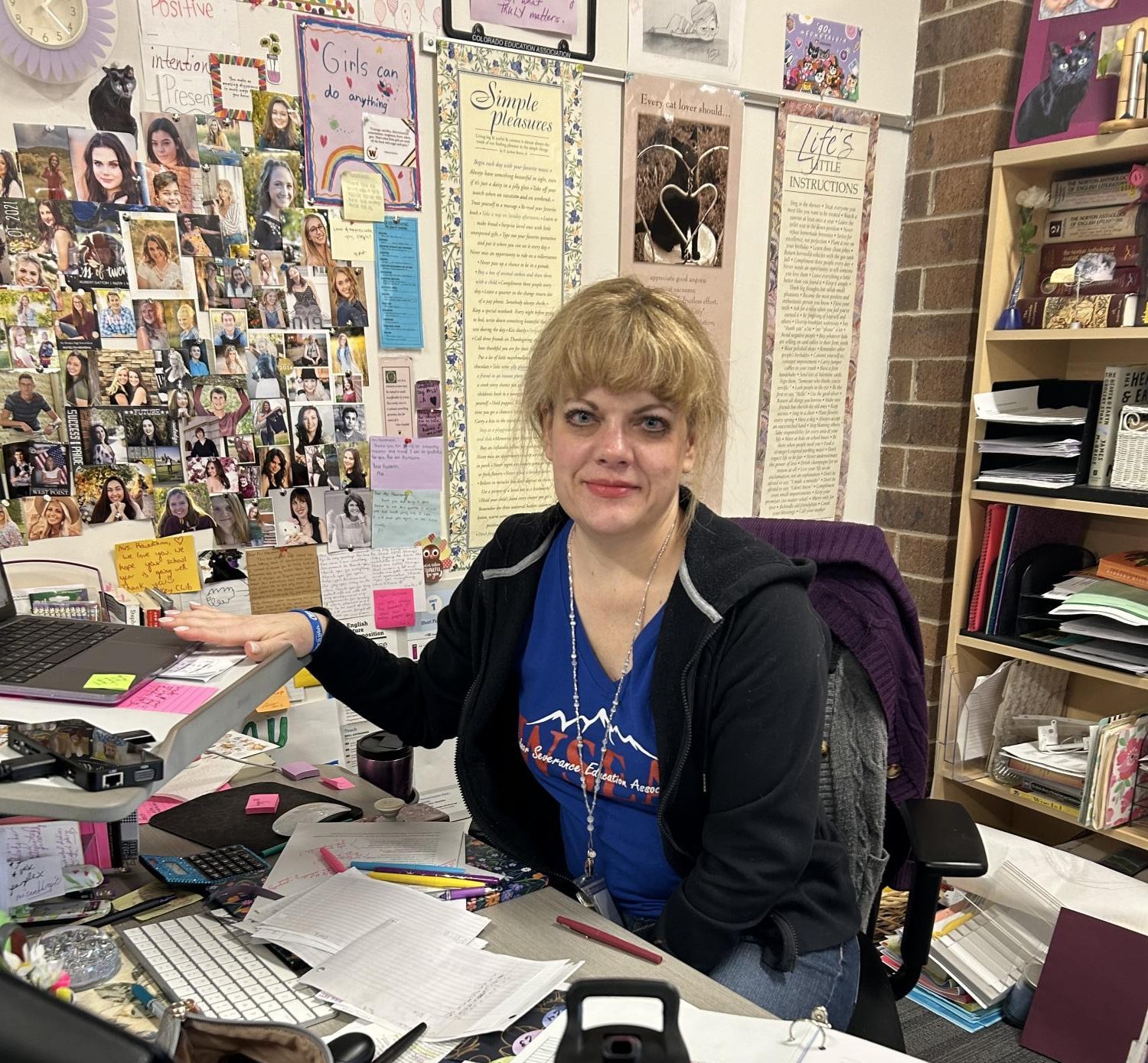 Stephanie Hausmann (staff) smiles while sitting at her desk. Half the battle with the SAT is becoming familiar with the testing format, Hausmann said.