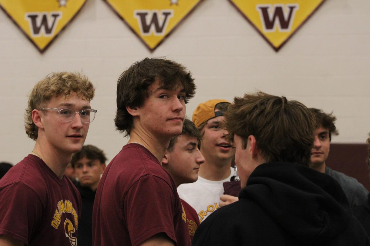 Mikey Munn (12) and Brady Lichtenberg (12) observe a full basketball court of students gathered to support the Wizards. The varsity boys took the win during their playoff game on Feb. 24. 