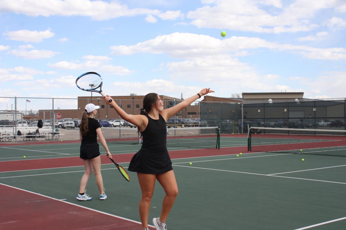 Abby Toerge (12) serves a play during practice at the tennis courts. The girls tennis team has struggled with spring weather affecting their practices and meets.