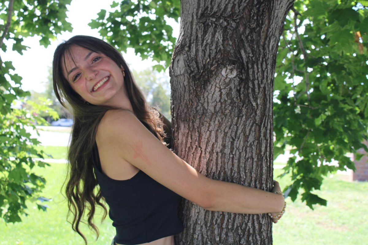 Michala Taylor hugs a tree and smiles