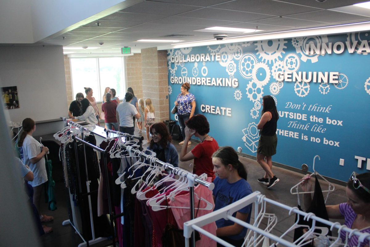 Students and parents peruse dress racks during the "Shop Til You Drop" event at the school on Friday, Sept. 6. Students could try on dresses and pick one to take home for homecoming.