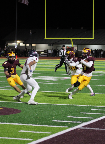 Football player runs with the ball while other football players chase him