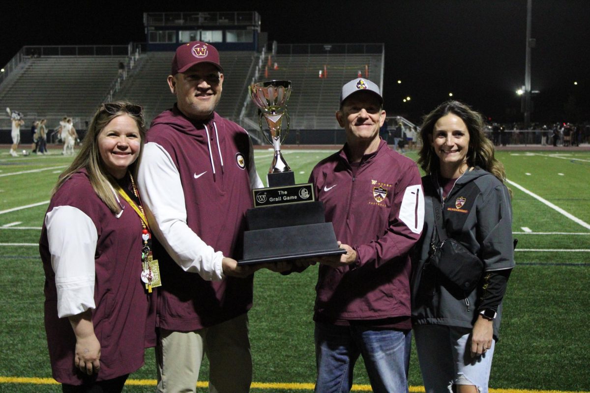 Four principals hold the Grail Game trophy and smile