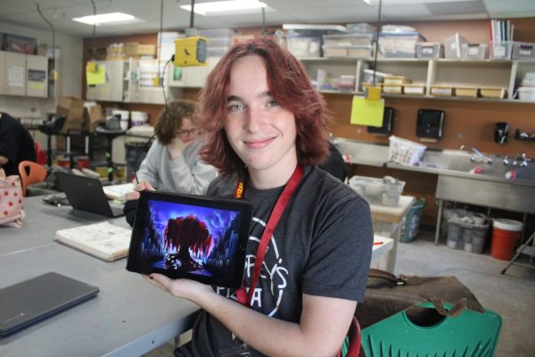 Student holds up artwork on tablet and smiles