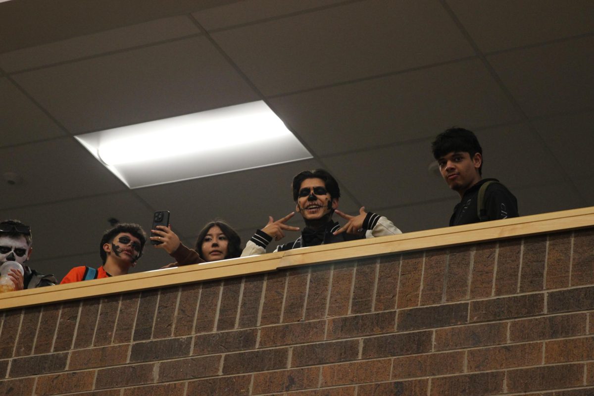 Joshua Rivera (12) and students look down from the balcony. Their faces were painted like skeletons for Halloween.