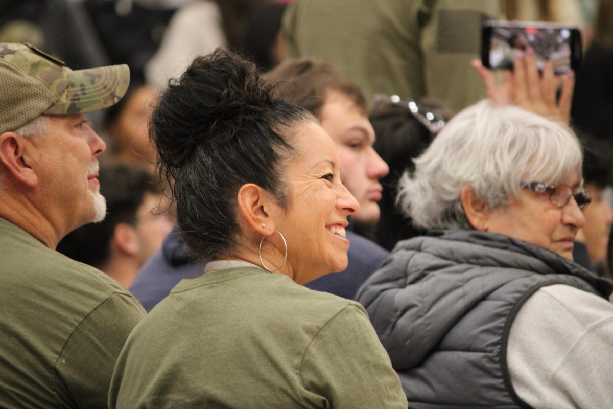 Audrey Bacon (staff) sits with her husband Richard Bacon in front of the podium as their daughter and Student Council executive co-president Leah Bacon (12) speaks. "It brought back memories of deployment and how hard it was," A. Bacon said. "So Leah in her speech was intentional about the families because she remembers it so well." 