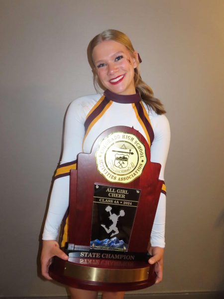 Cheerleader holds trophy and smiles