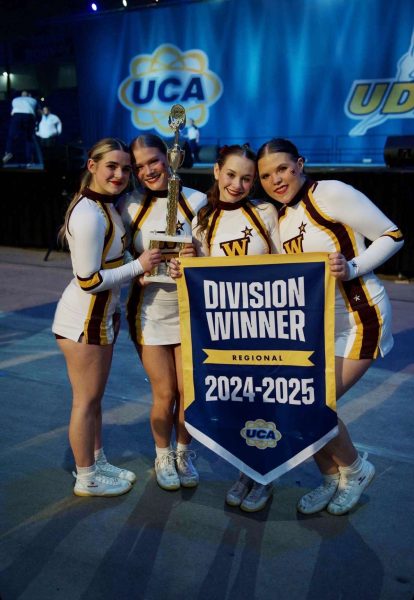 four cheerleaders hold a trophy and a sign that says 20024-2025 division winner