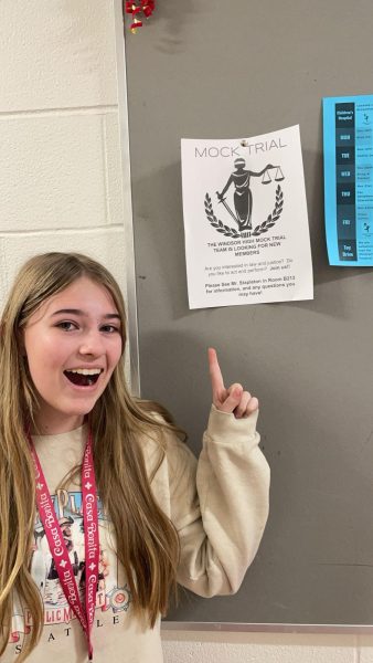 Student points to a poster and smiles