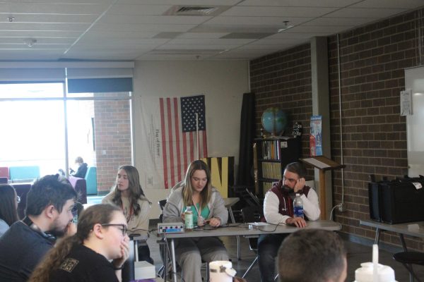 Students and a staff member sit at a desk