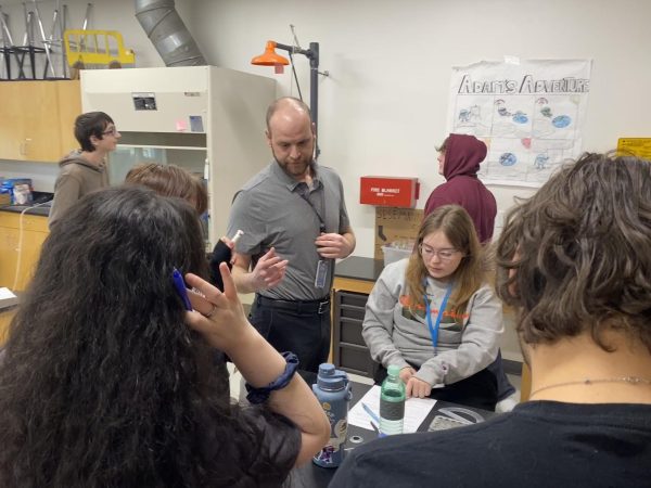 teacher talks with students in a chemistry lab