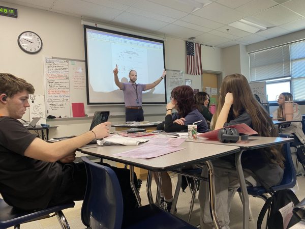 Jeffrey Sesemann (staff) explains an assignment to advanced chemistry students. Sesemann walked around the classroom asking questions to help the students understand. 