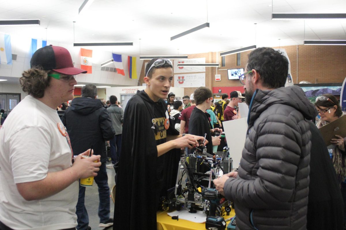 Cooper Dunworth (10) watches as Adam Kirkpatrick (12) answers questions about his team's robot. "I got involved because of the intro to robotics course," Kirkpatrick said. "Because before that, I had a little coding experience, a little bit of software stuff, but I hadn't done as much electrical circuit design and, like, mechanical stuff." 