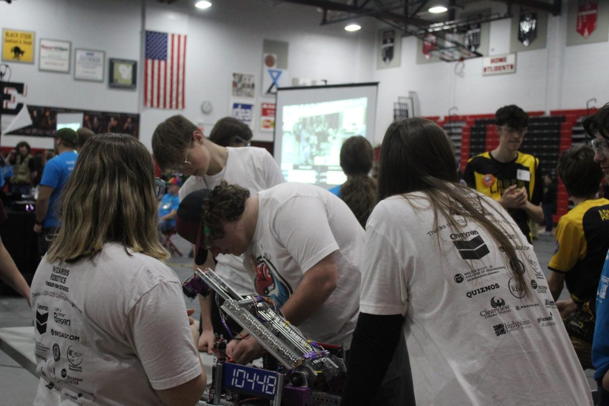 Teammates on Team Štír prepare their robot at the queuing table. Dunworth explained, "We all just go there so we can set down our robots and talk with the other people on our alliance to just kind of strategize for the match."