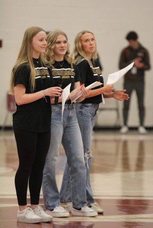 Three students stand and listen to a speaker