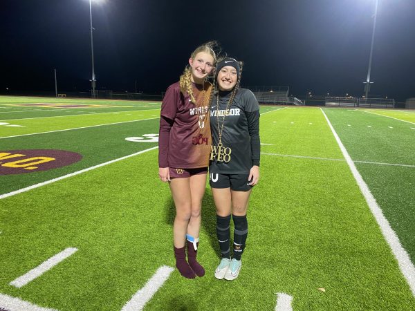 two soccer players stand and smile