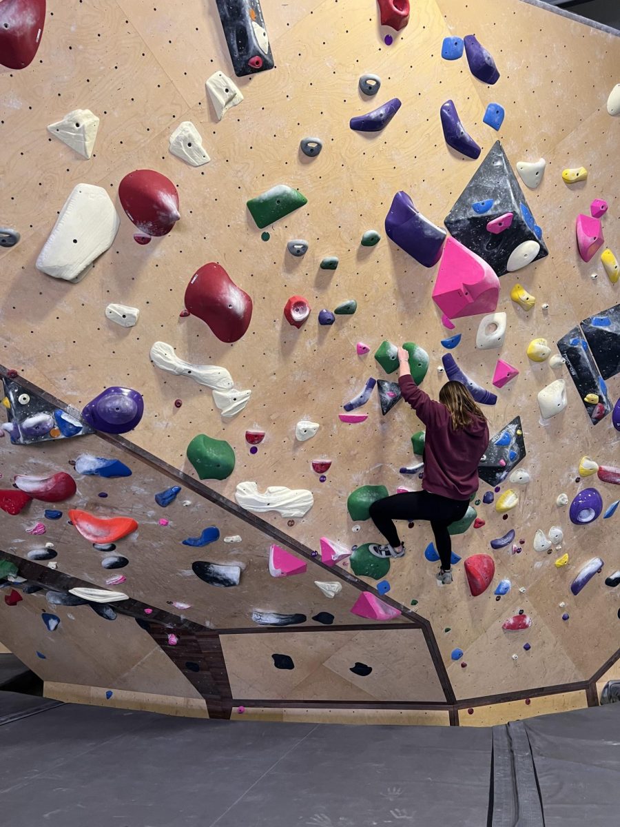 Sienna Hawbaker (12) reaches for a hold during a field trip to Loveland Climbing Collective. The adventure ed class teaches students safety and life skills in the classroom and on field trips.