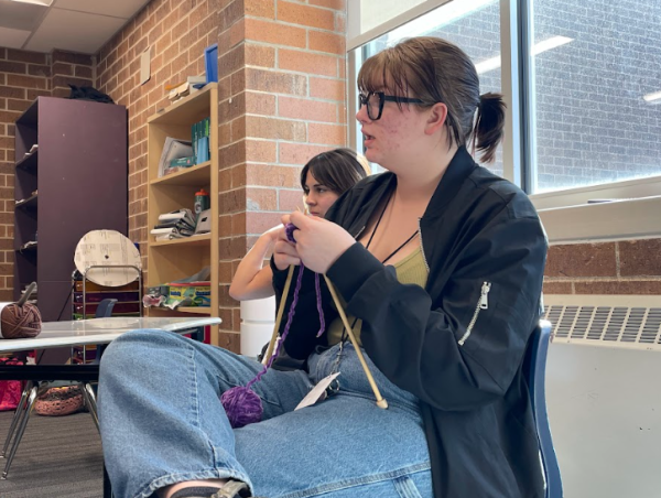 Student sits in class and crochets