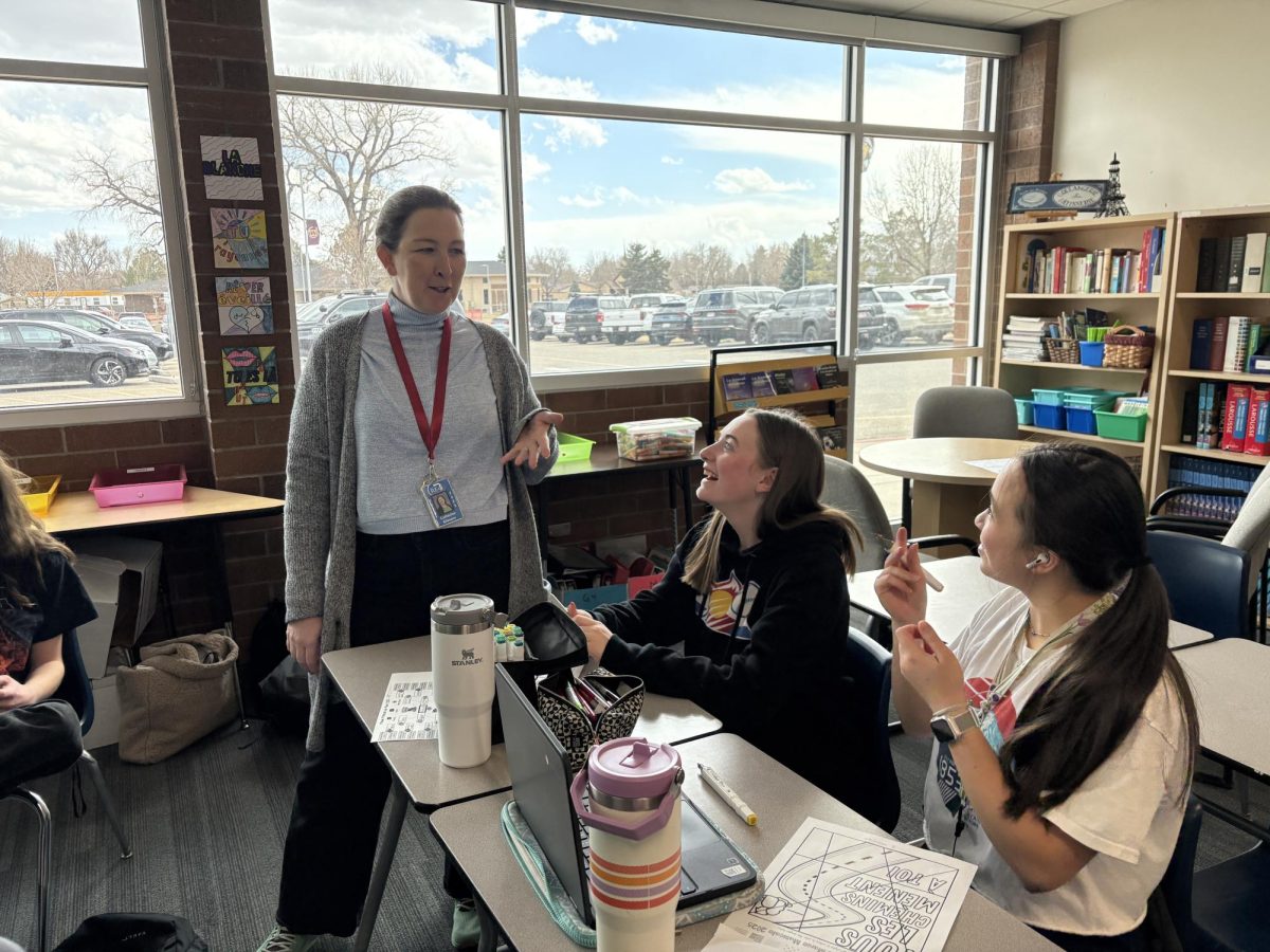 French and Spanish teacher Cathy Gilmore (staff) explains an assignment to Payton Johnson (10) and Sadie Sapinoro (10). This was during 'Manie Musicale," a French music competition that ranks French music similarly to March Madness.