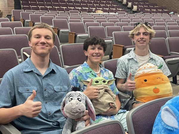 Students hold plushies and smile