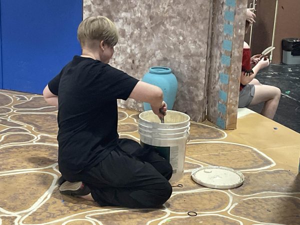 Student paints as part of the construction and painting crews