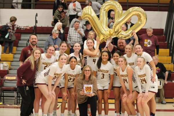 Team poses with balloons that spell 100