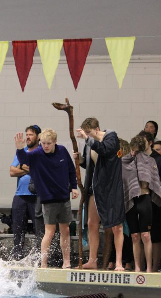Two swimmers stand on the deck and cheer